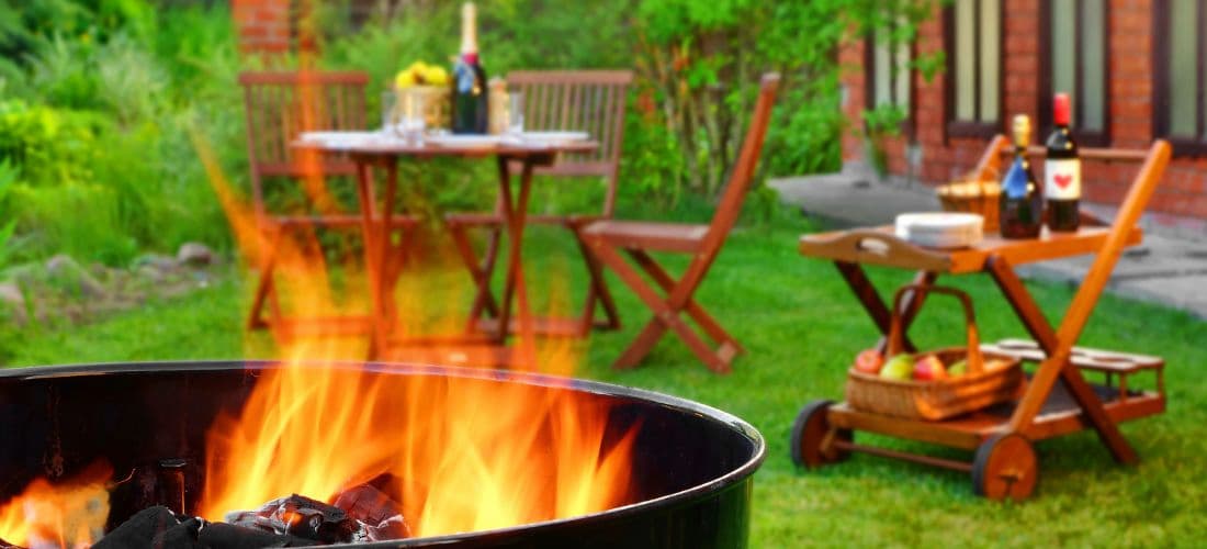 Grill lit up with wine on tables for backyard bbq